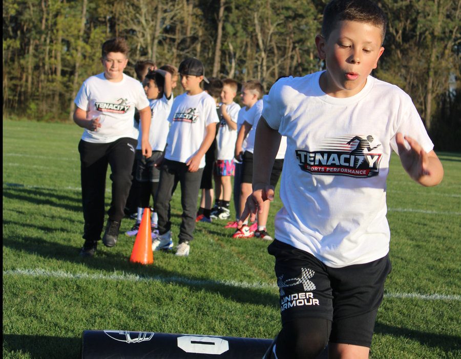 Young athletes in Tenacity Sports Performance shirts running drills