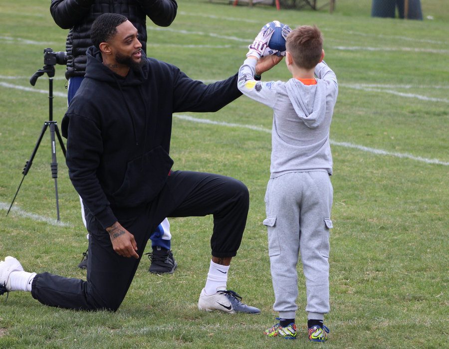 Tenacity coach working with a young football athlete during team training